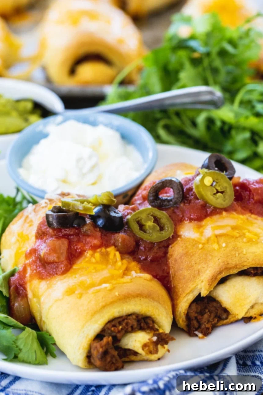 Close-up of baked Crescent Beef Burrito Bundles, generously topped with fresh salsa and black olives, ready to be enjoyed as a simple family meal.