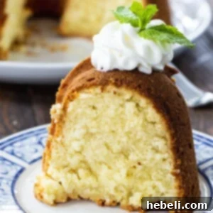 Luscious Coconut Cream Cheese Pound Cake 5 Slice of cake topped with whipped cream and a mint leaf garnish.