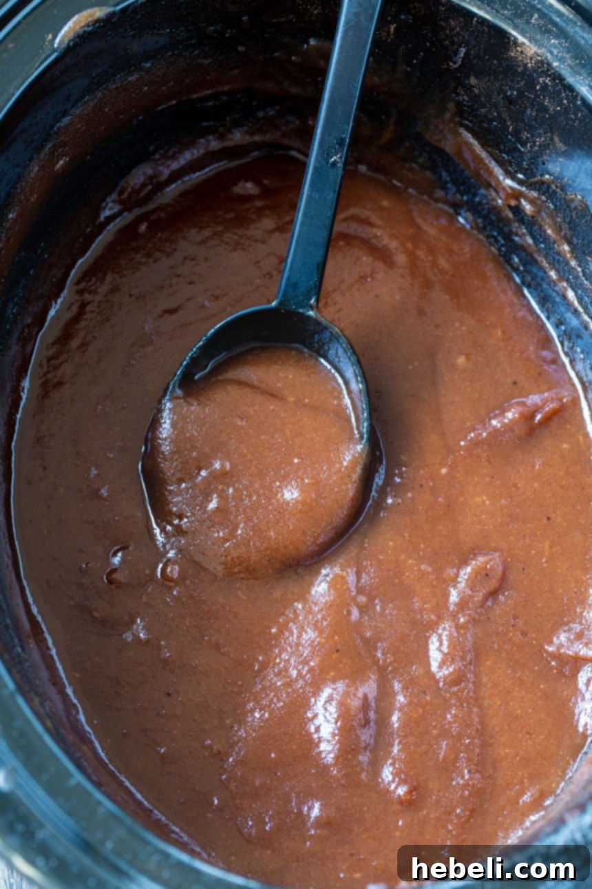 Homemade Slow Cooker Apple Butter 3 Apple Butter in slow cooker with spoon scooping it.