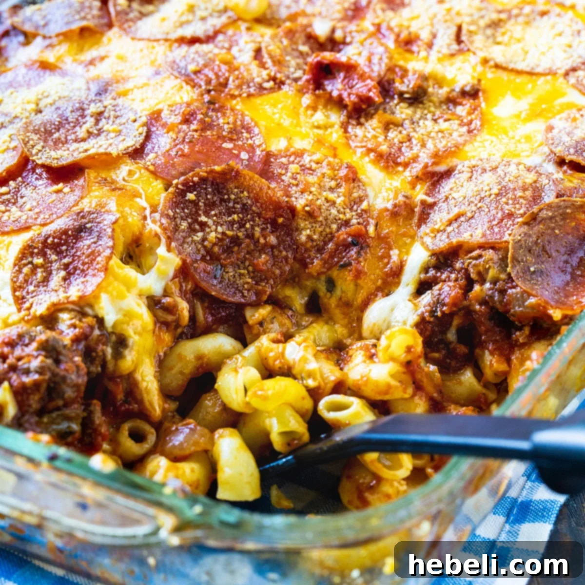 Spoon scooping up Johnny Marzetti Casserole in a 9x13-inch dish.