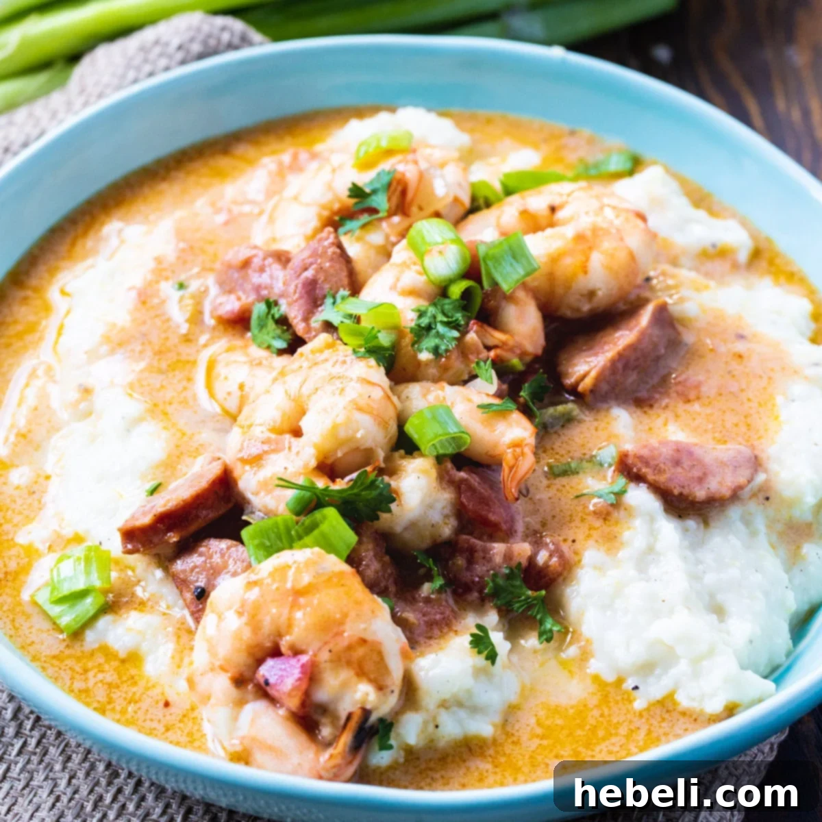 A vibrant bowl of Smothered Shrimp and Parmesan Grits, richly topped with green onions.