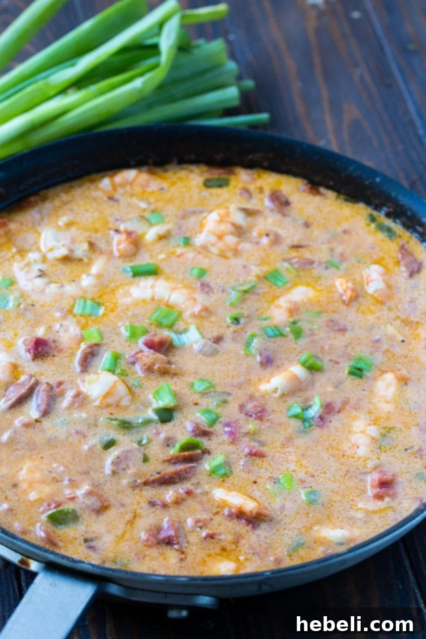 Close-up of Smothered Shrimp simmering in a large skillet, ready to be served over grits.