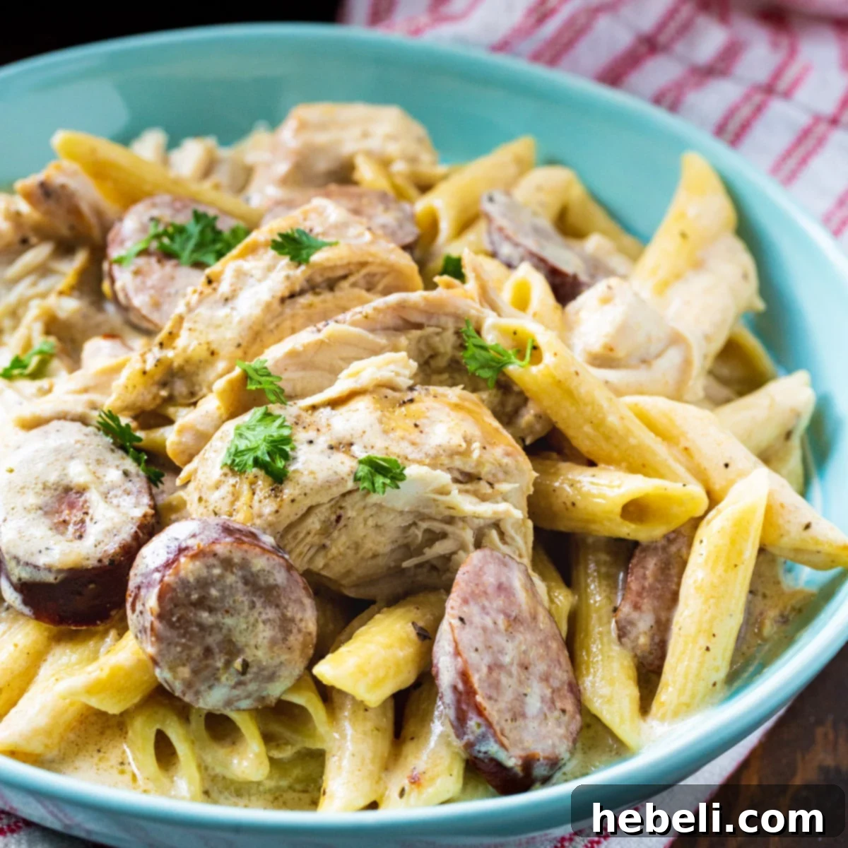 Slow Cooker Cajun Chicken Alfredo in a blue bowl, garnished with parsley.