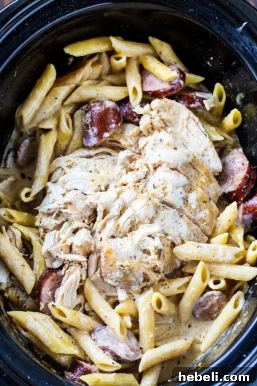 Close-up of Slow Cooker Cajun Chicken Alfredo with Sausage bubbling in a crock pot.