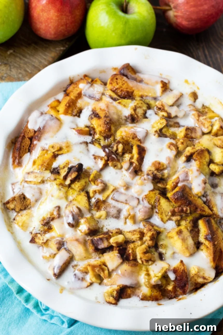 Unbaked Apple Cinnamon Roll Bake in a pie pan, surrounded by fresh apples, ready for the oven.
