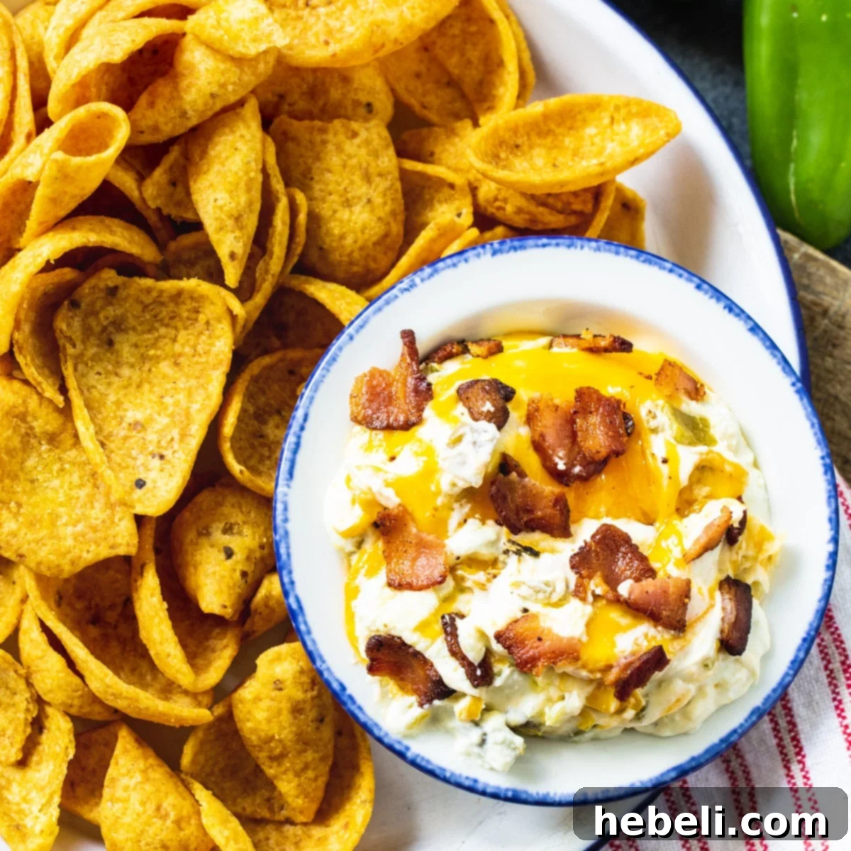 Ultimate Slow Cooker Jalapeno Popper Dip 2 Creamy Slow Cooker Jalapeno Popper Dip in a rustic bowl, surrounded by crunchy Fritos for dipping, ready to be served at a party.