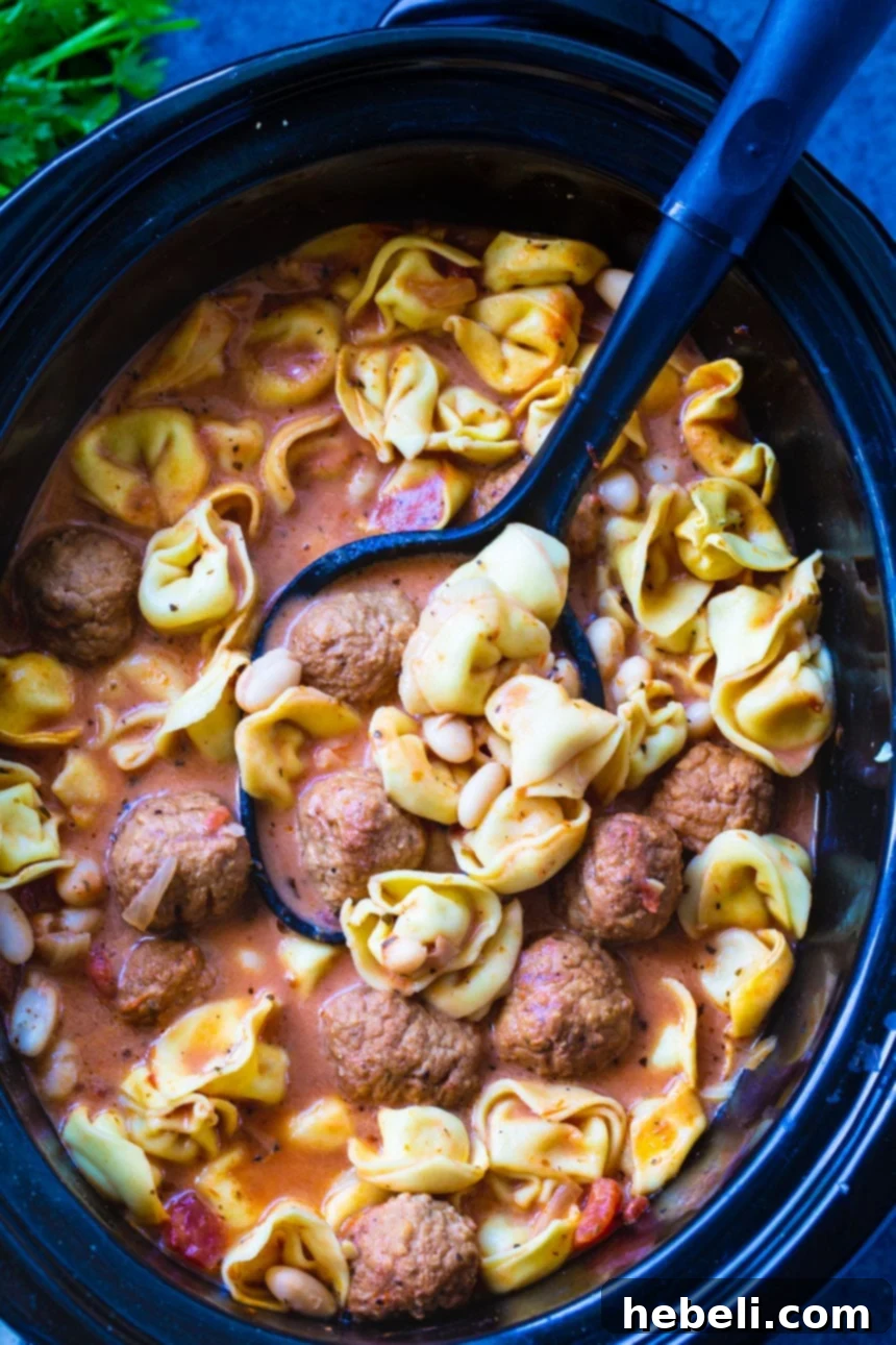 Crockpot Meatball Tortellini Soup 3 A spoon scooping creamy Meatball and Tortellini Soup from a slow cooker, showcasing the rich texture and delicious ingredients.