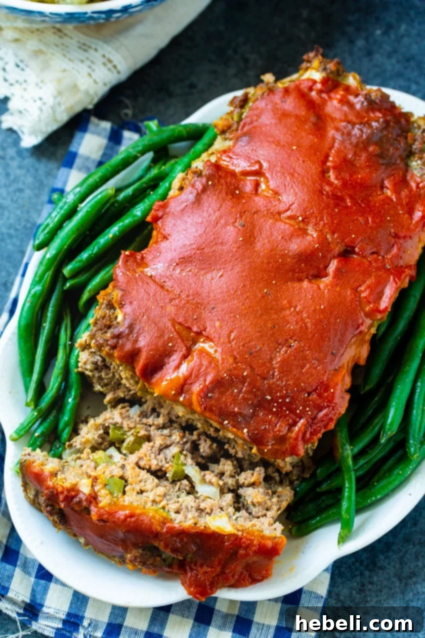 Classic Homestyle Meatloaf 3 Overhead view of Old School Meatloaf with one slice cut, showcasing the tender interior and rich tomato glaze.