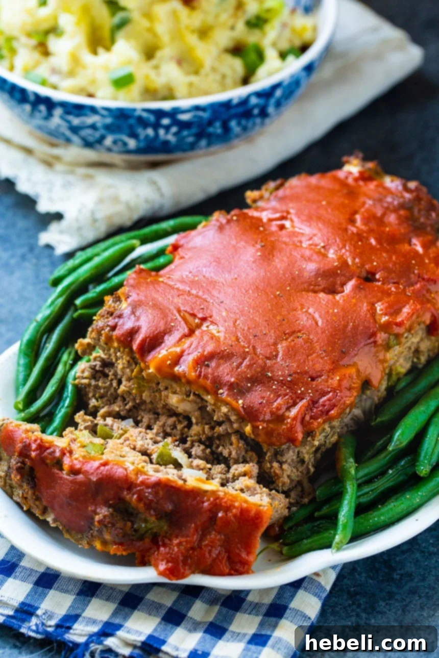 Classic Homestyle Meatloaf 4 Old School Meatloaf served on a plate with fluffy mashed potatoes and vibrant green beans in the background.