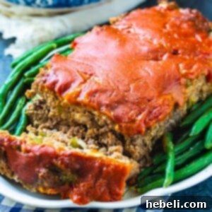 Meatloaf on serving plate with green beans.