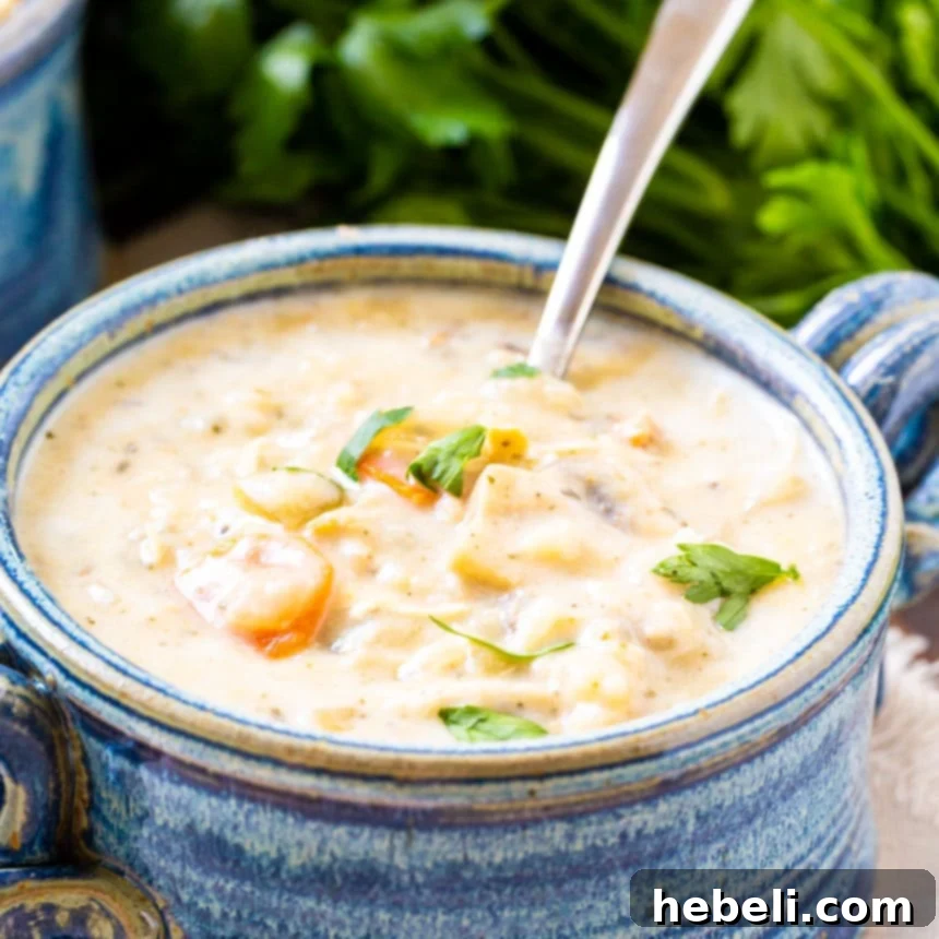 Creamy Chicken Soup in a blue bowl, garnished with fresh herbs.