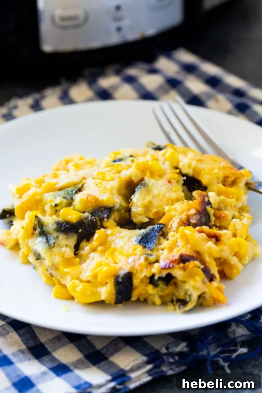 A generous serving of Slow Cooker Southwestern Corn Casserole on a white plate, showcasing its creamy texture and vibrant ingredients.