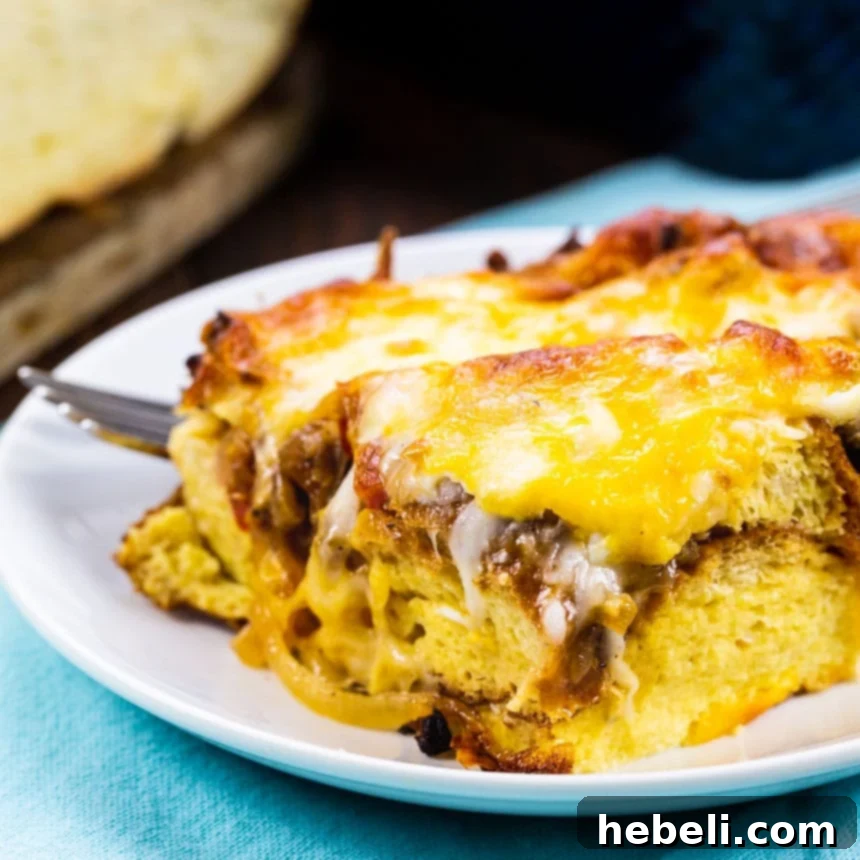 A perfectly portioned slice of golden-brown breakfast casserole, showcasing layers of bread, sausage, onions, and melted cheese, ready to be enjoyed.