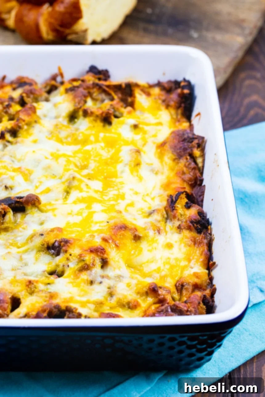 A vibrant Overnight Sausage and Caramelized Onion Breakfast Casserole resting in a blue baking dish, its rich ingredients visible and ready for the oven.