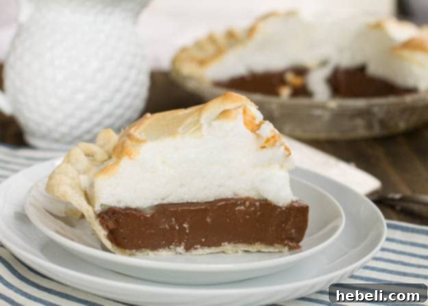 A generous slice of Old-Fashioned Chocolate Meringue Pie, showing its glossy, peaked meringue and rich chocolate custard filling.