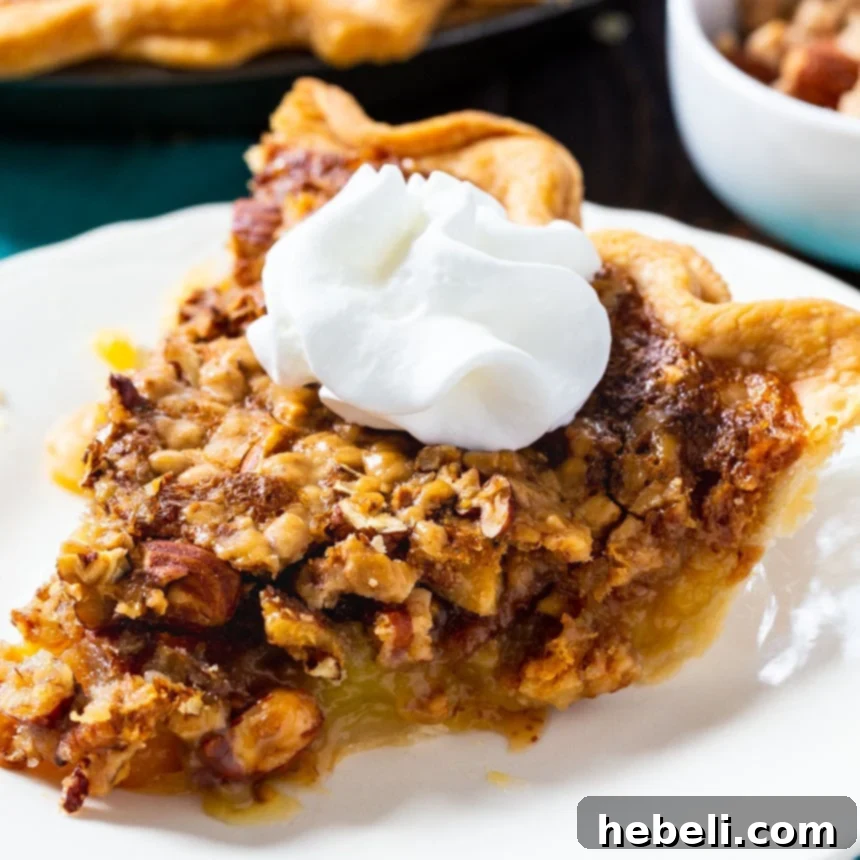 A slice of Toffee Nut Pie, generously topped with whipped cream, displaying its inviting nutty and toffee-filled texture.