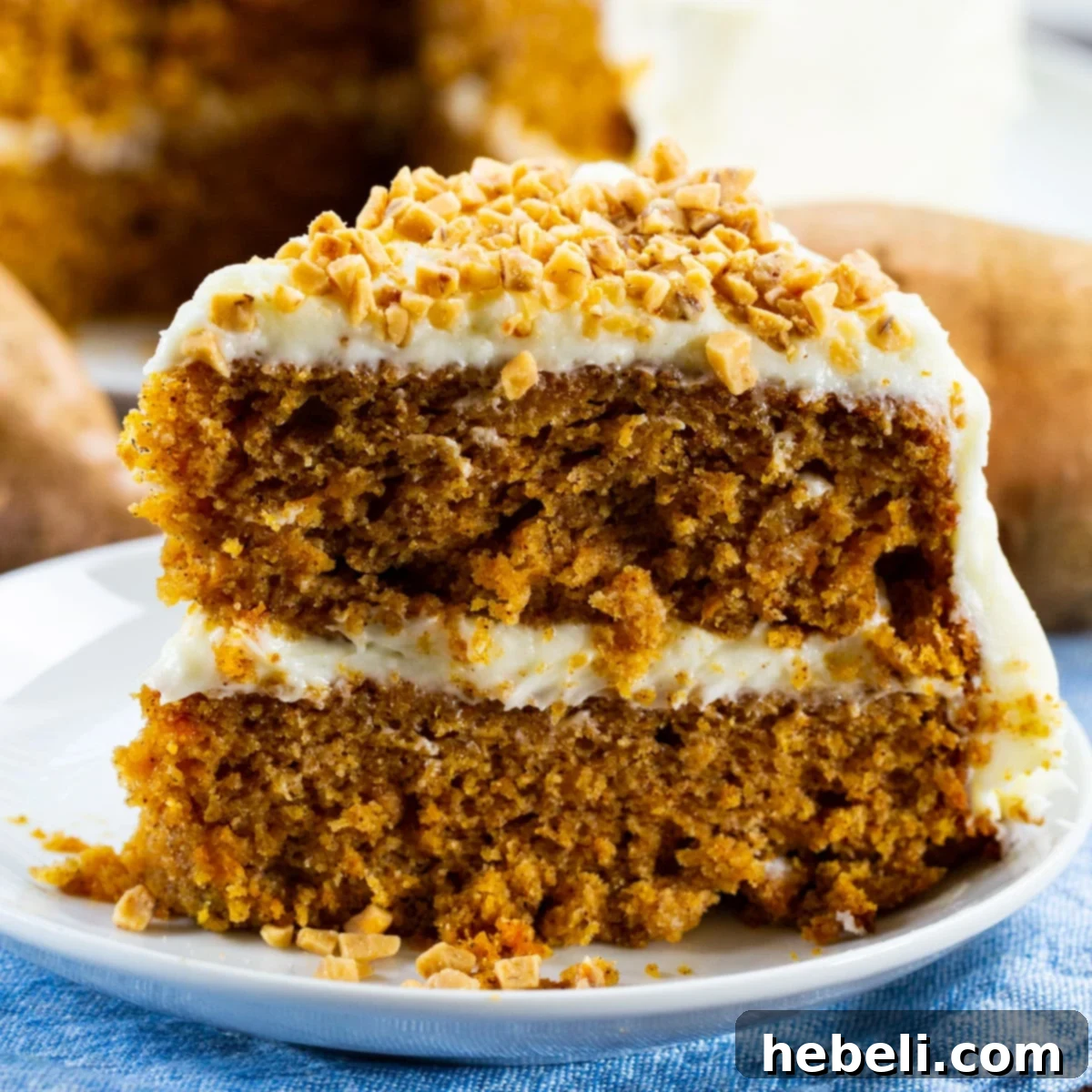A beautiful slice of Sweet Potato Layer Cake, showing its multiple moist layers of cake, creamy frosting, and crunchy toffee bits.