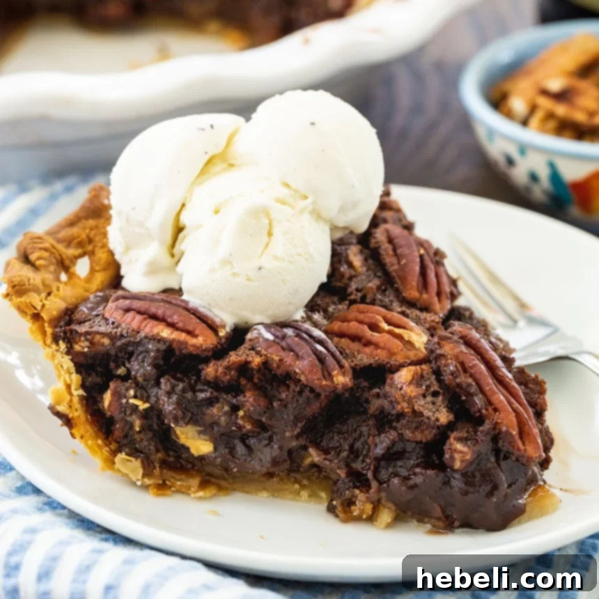 A perfectly sliced piece of Mocha Pecan Pie, topped with a scoop of vanilla ice cream, showing its rich, dense texture and appealing layers.
