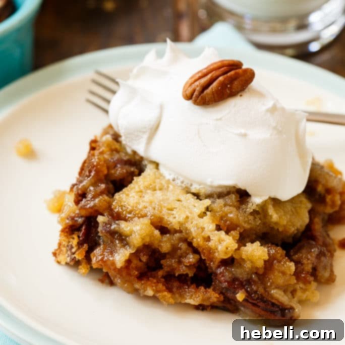 A slice of Pecan Pie Cake, revealing its moist texture and pecan filling, served elegantly with a scoop of vanilla ice cream.