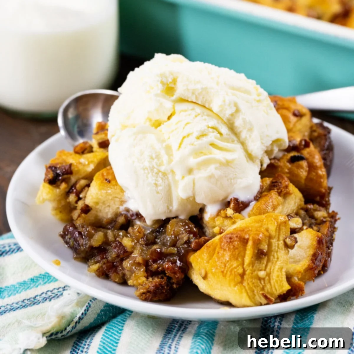 A piece of Pecan Pie Bubble Up, topped generously with vanilla ice cream, showing the soft, biscuit dough base and gooey filling.
