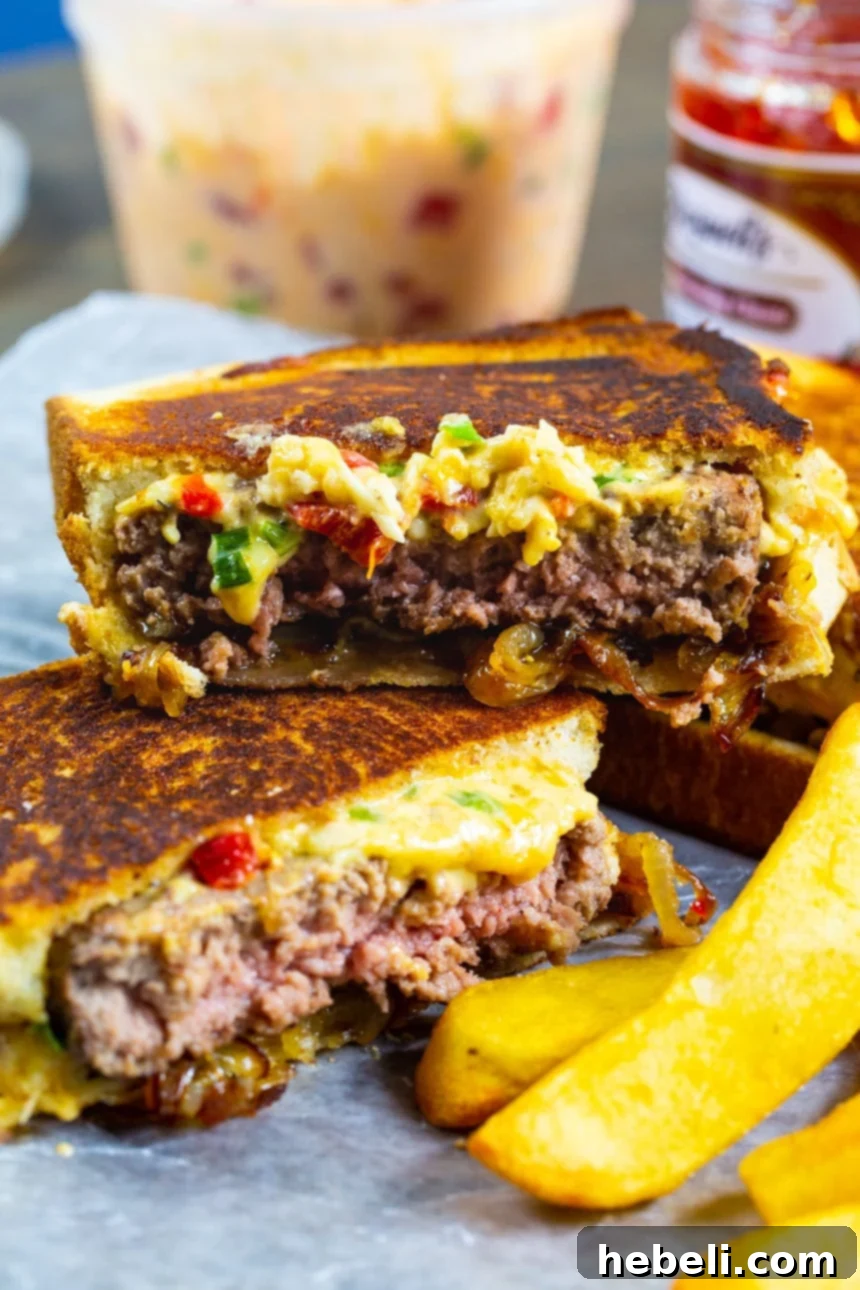 Gooey Pimento Cheese Patty Melts 3 Pimento Cheese Patty Melt cut in half with fries.