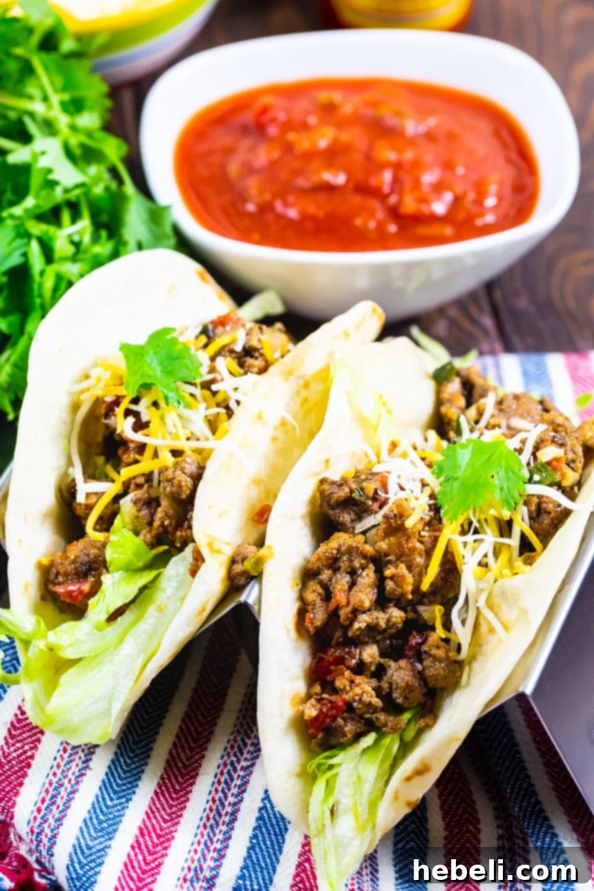Your New Favorite Taco Meat 4 Two hearty tacos featuring the Best Ever Taco Meat, garnished with fresh toppings, with salsa and lime in the background.