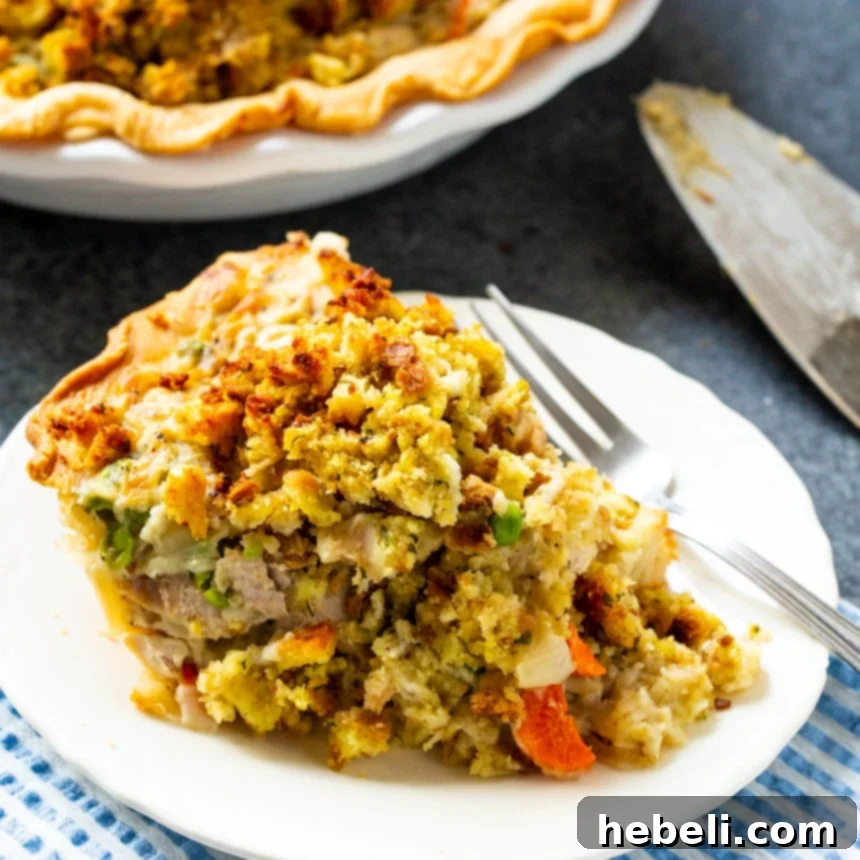 A generous slice of Turkey Pot Pie with Stuffing Topping on a white plate, revealing its rich filling.