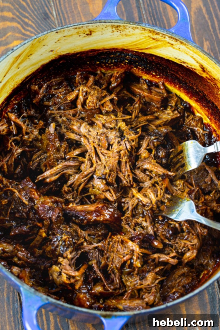 Smoky Pulled Beef 4 Shredding tender beef with two forks in a Dutch oven.