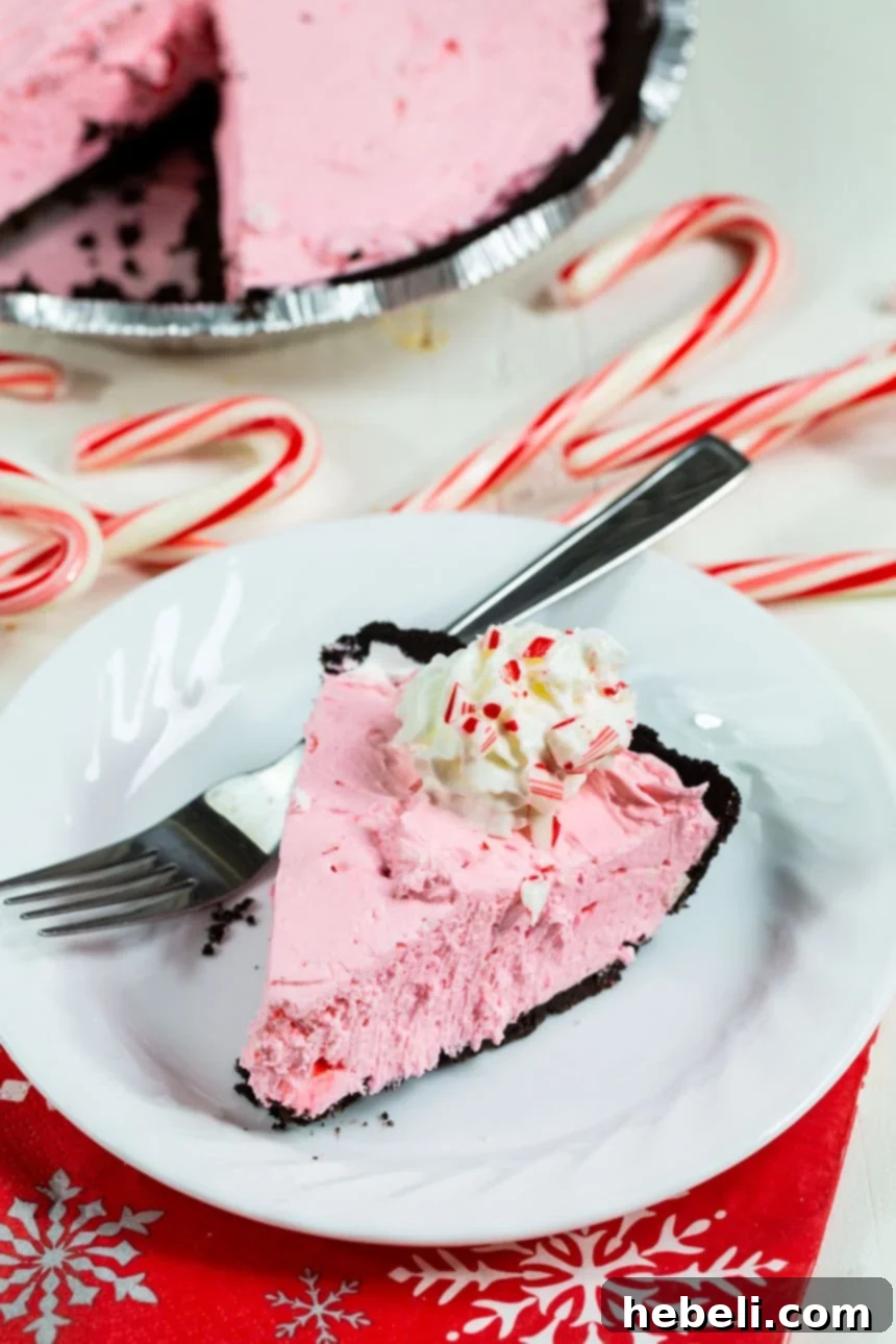 A delectable slice of No-Bake Peppermint Pie on a plate, elegantly adorned with miniature candy canes, capturing the festive spirit.