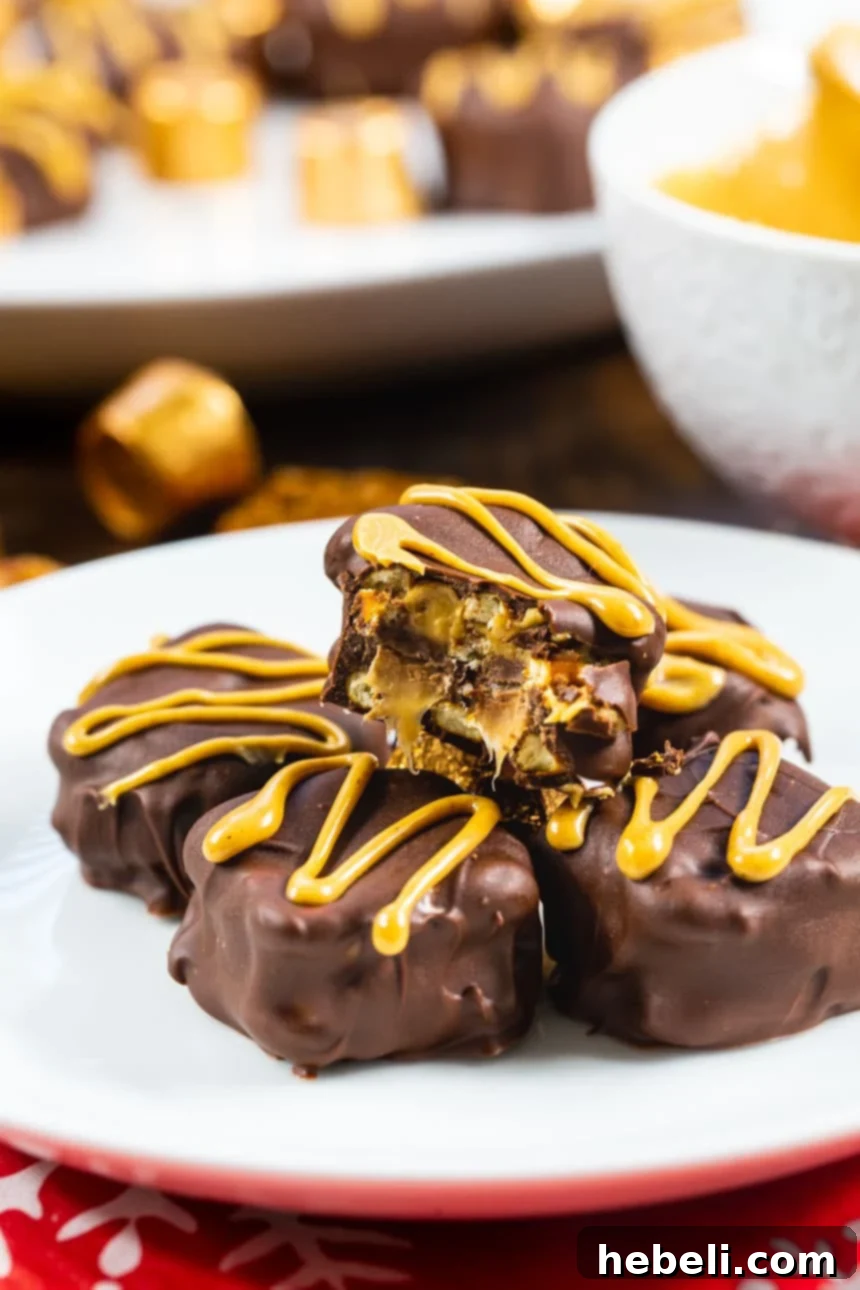 Sweet and Salty Rolo Pretzel Bites 5 A Rolo Pretzel Sandwich with a small bite taken out, revealing the gooey caramel and peanut butter filling within the chocolate coating.