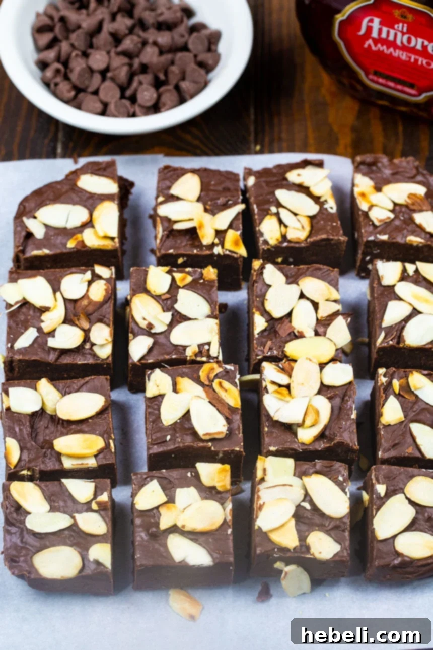 Decadent Chocolate Amaretto Fudge squares alongside a bowl of assorted chocolate chips.