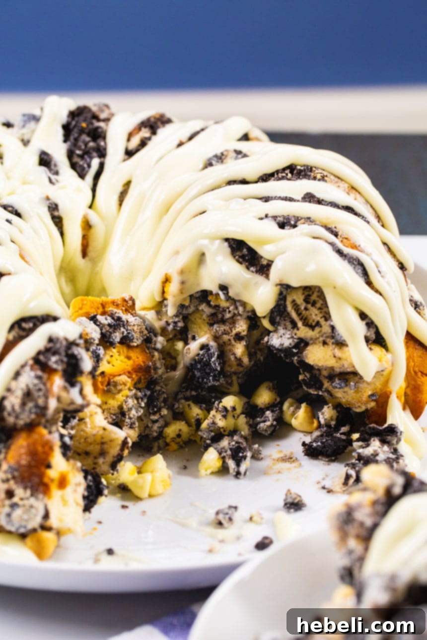 Monkey Bread with a piece gently pulled out, revealing its soft, gooey interior with crushed Oreos and white chocolate.