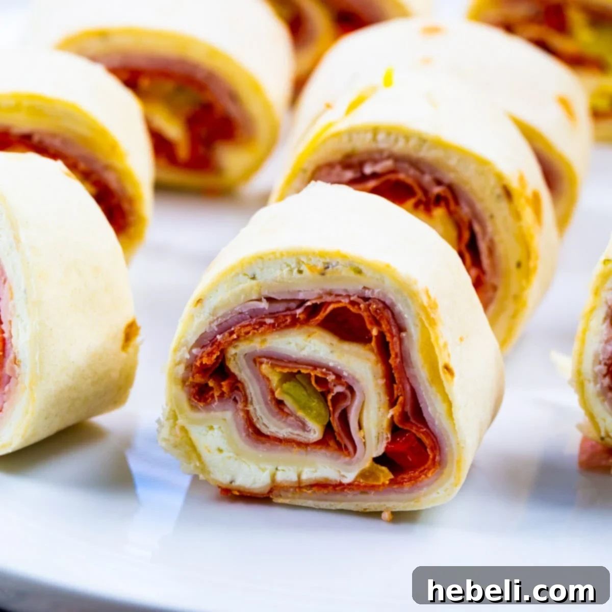 Zesty Italian Swirls 2 Delicious Spicy Italian Pinwheels arranged artfully on a white plate, ready to be served as an appetizer or snack.