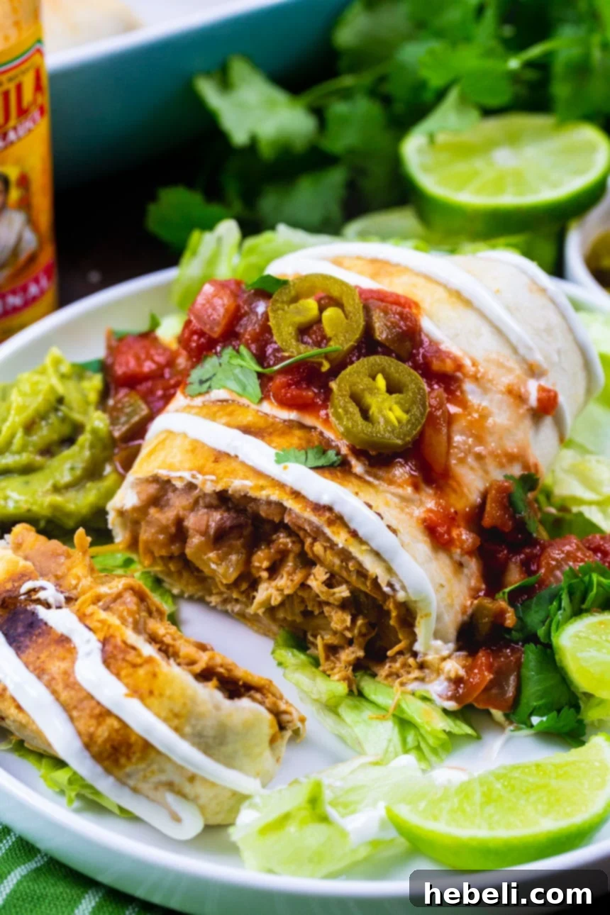 Crispy Baked Chicken Chimichangas 4 Close-up of a Chicken Chimichanga on a plate with toppings like salsa, guacamole, and sour cream.