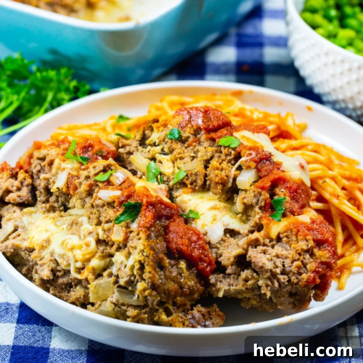 Two generous slices of Mozzarella Stuffed Meatloaf served on a plate with pasta, showcasing the melted cheese interior.