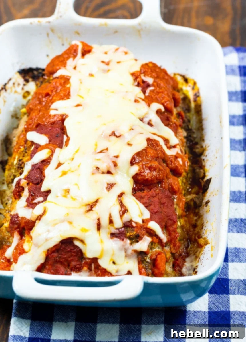 The Mozzarella Stuffed Meatloaf baking in a glass dish, covered in pasta sauce.