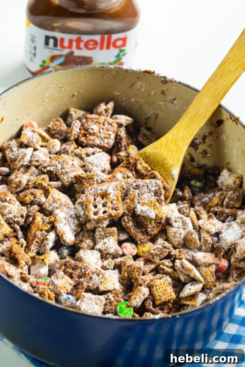 Nutella Muddy Buddies being mixed in a large Dutch oven pot, showcasing the coating process.
