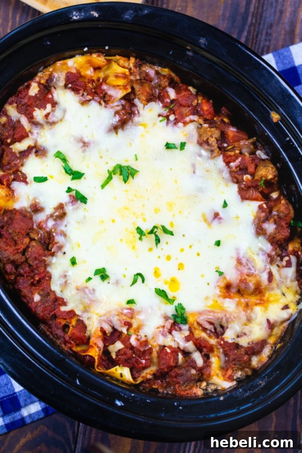 Close-up of a bubbling slow cooker sausage lasagna, showing melted cheese and rich sauce.