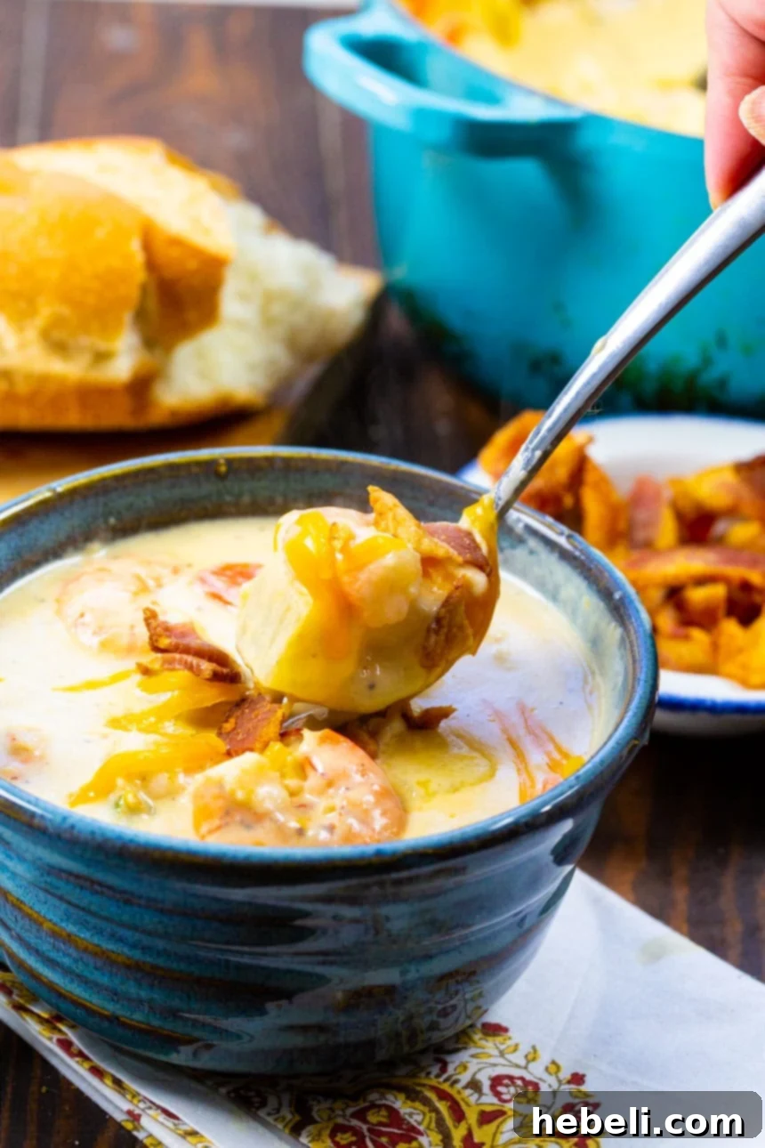 Shrimp and Potato Chowder 4 A spoon expertly scooping a generous portion of Creamy Potato Soup with Shrimp from a blue bowl.