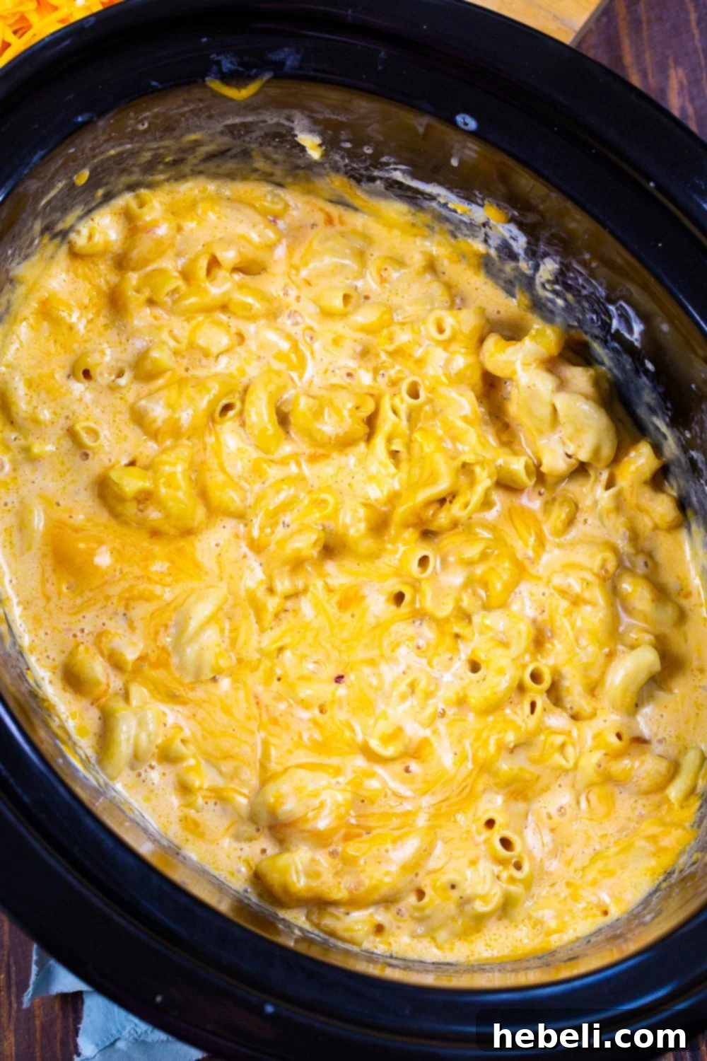 Close-up shot of creamy Mac and Cheese bubbling gently in a slow cooker, ready to be served.