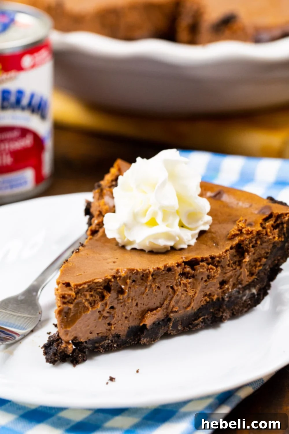 Velvety Chocolate Dream Pie 4 A tempting slice of Sweetened Condensed Milk Chocolate Pie adorned with a cloud of whipped cream on top, ready to be enjoyed.