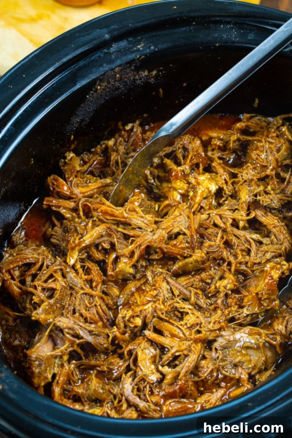 A large Boston butt coated in a smoky spice rub, ready to be cooked in a slow cooker, promising tender, flavorful pulled pork.