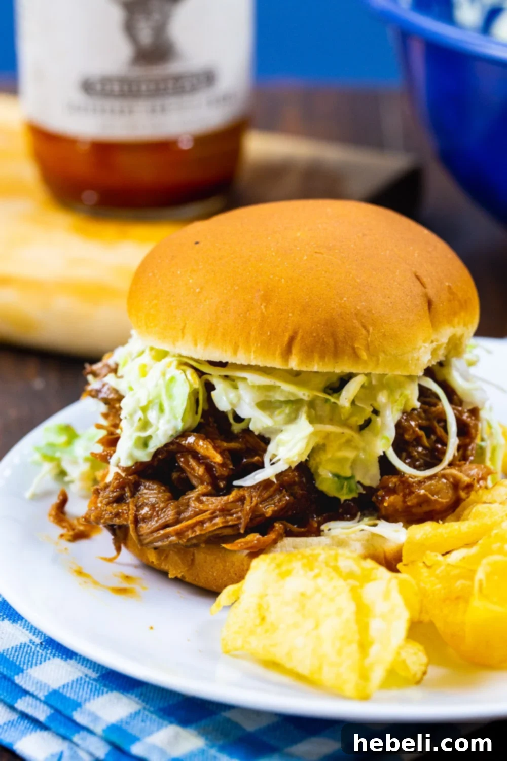 A close-up shot of a smoky pulled pork sandwich on a bun, topped with creamy coleslaw, highlighting its mouth-watering texture.