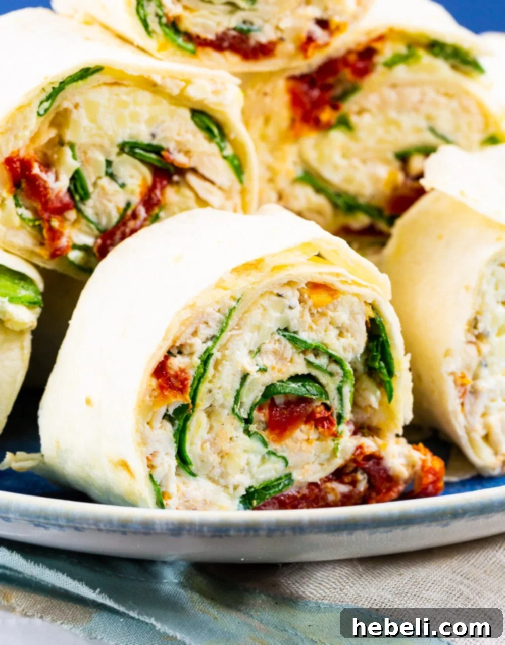 Creamy Tuscan Chicken Pinwheels 3 Close-up of a perfectly sliced Tuscan Chicken Pinwheel, revealing the creamy chicken, spinach, and sun-dried tomato filling.