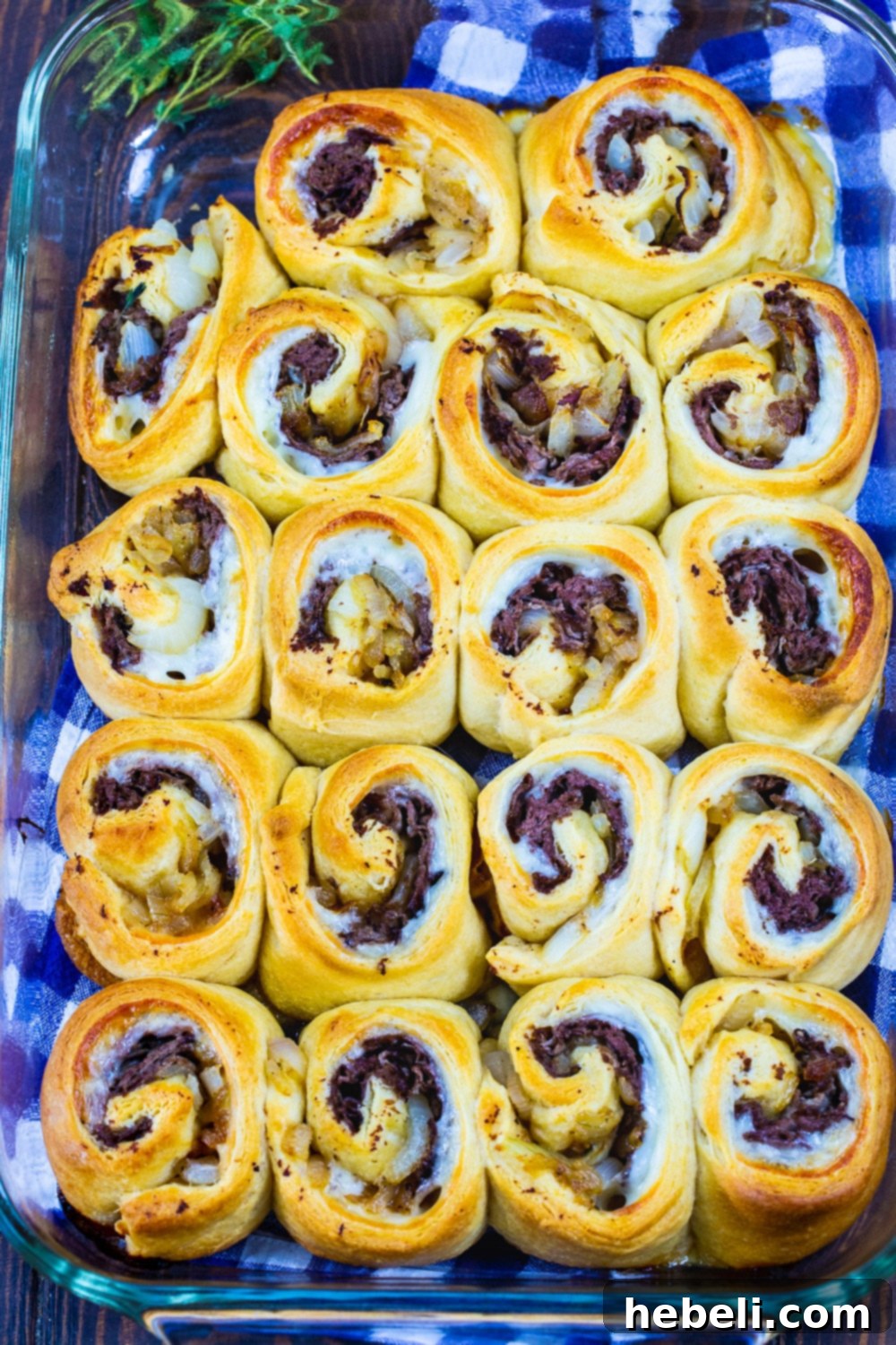 Flavorful French Dip Roll-Ups 3 French Dip Pinwheels arranged neatly in a baking dish, ready for the oven or freshly baked and golden.