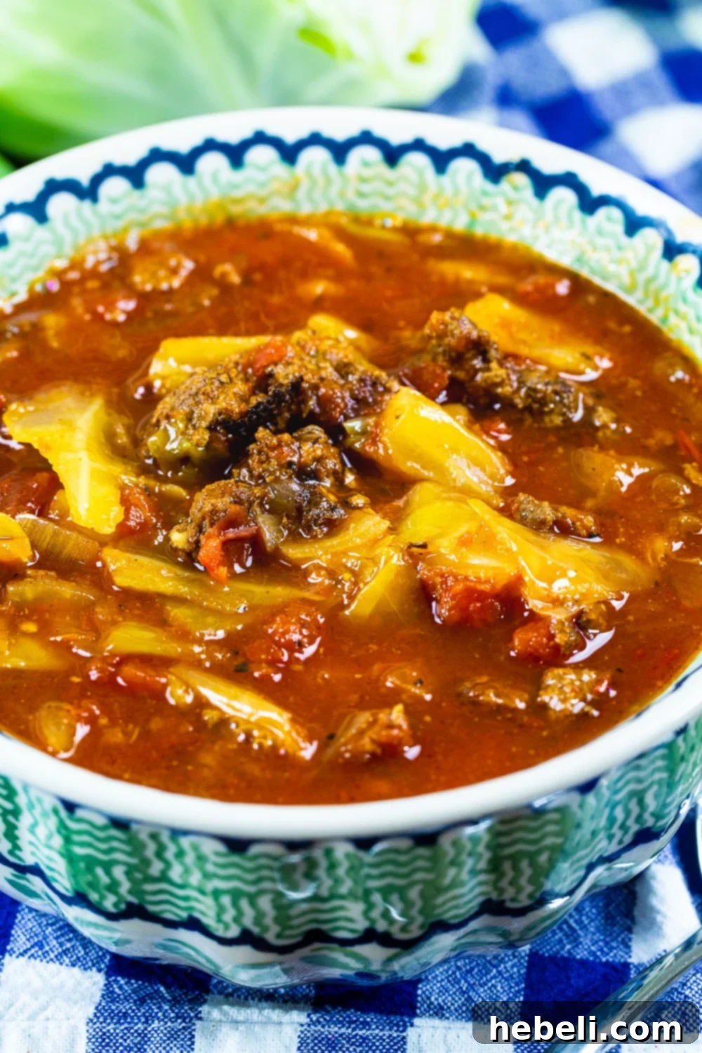 A close-up shot of a steaming bowl of Slow Cooker Spicy Cabbage Beef Soup, garnished with fresh green herbs, ready to be enjoyed.