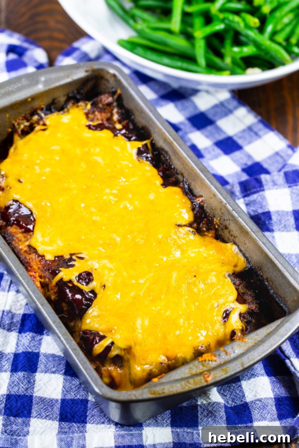 Gooey Cheesy Chipotle Meatloaf 3 A freshly baked Cheesy Chipotle Meatloaf, still in its baking pan, glistening with a rich glaze and melted cheese, ready to be sliced and served.