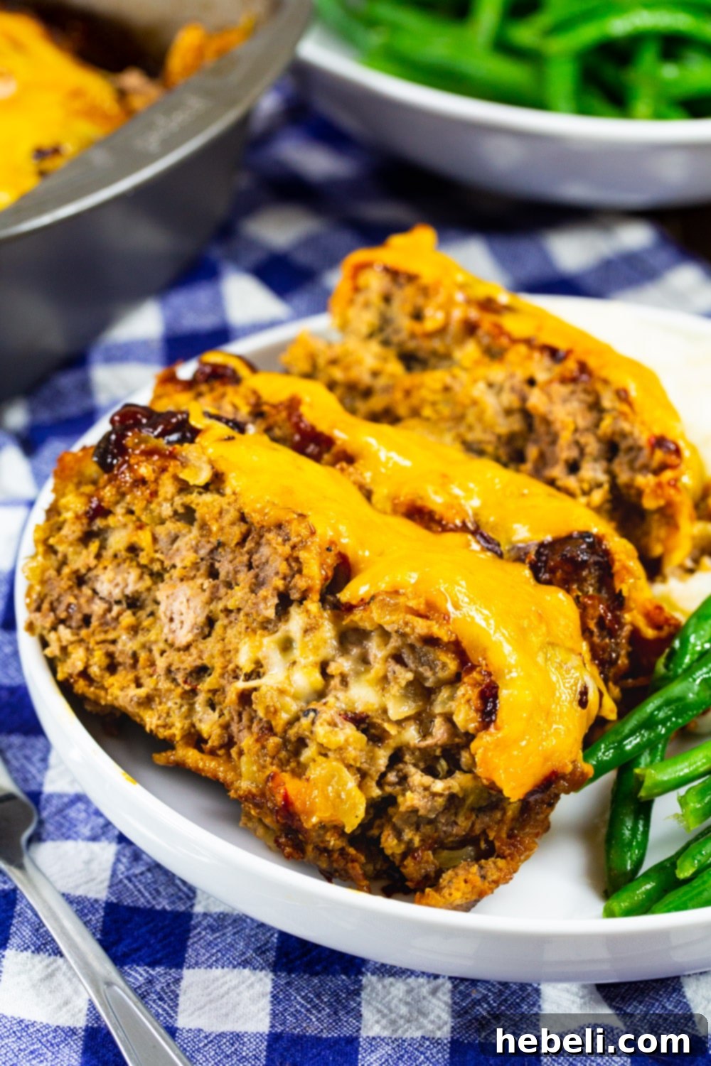 Gooey Cheesy Chipotle Meatloaf 4 Three slices of the decadent Cheesy Chipotle Meatloaf, beautifully plated with the melted cheese and glaze visible, showcasing its inviting texture and rich color.