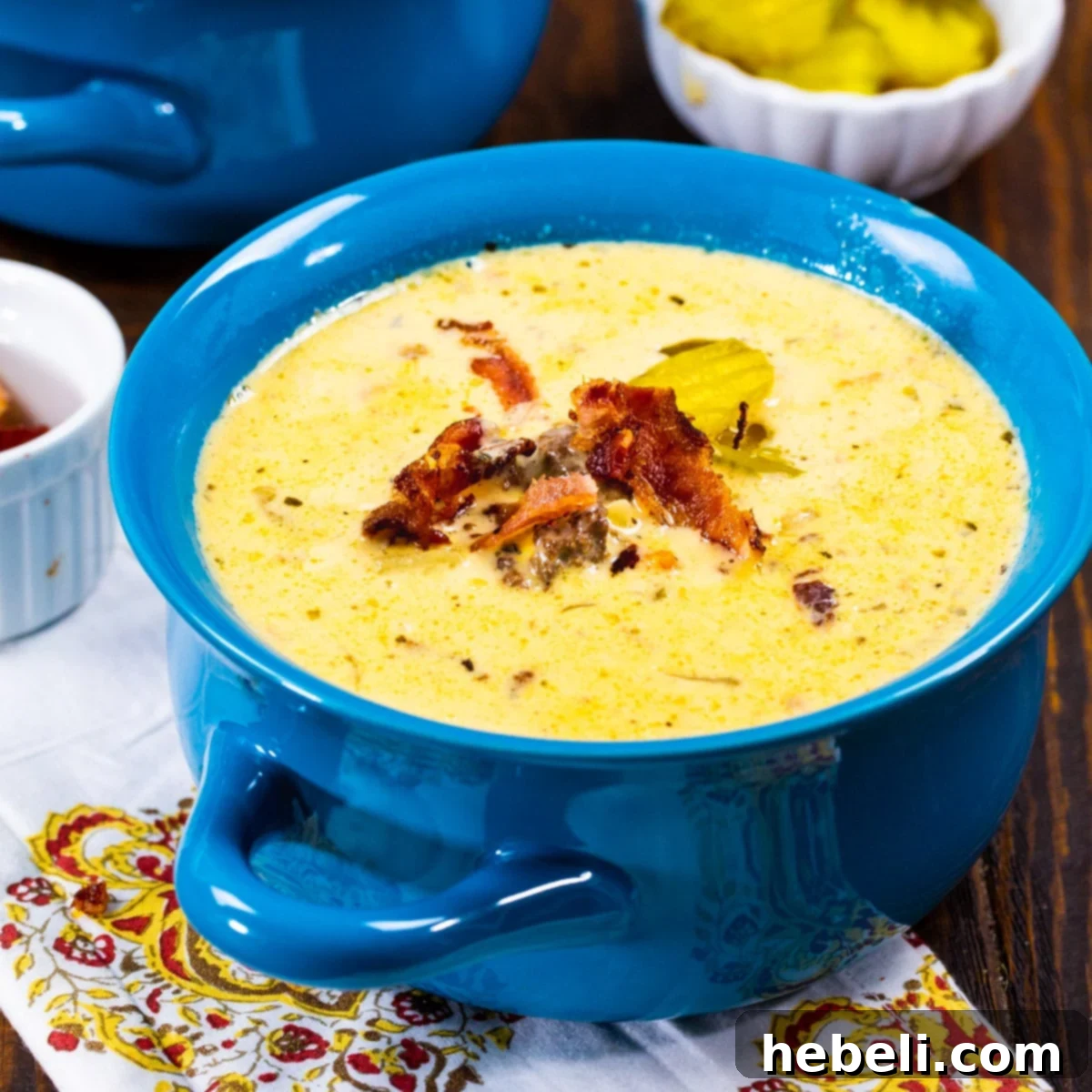 Loaded Slow Cooker Bacon Cheeseburger Soup 2 A hearty bowl of Slow Cooker Bacon Cheeseburger Soup, garnished with crumbled bacon and fresh parsley, sitting on a rustic wooden table.