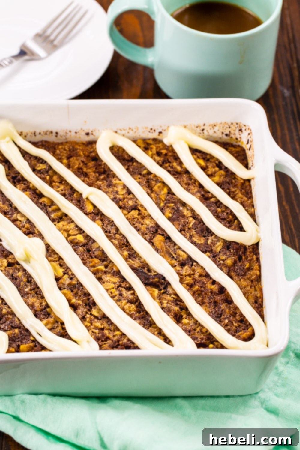 Baked Oatmeal topped with a generous swirl of cream cheese glaze still in the baking dish, ready to be served.